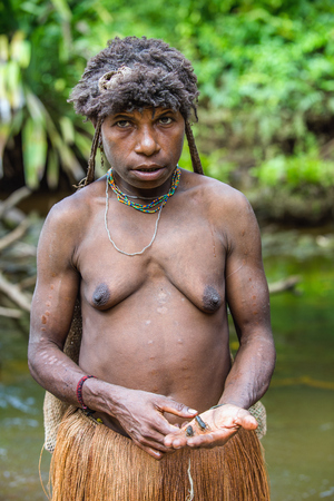 WILD JUNGLE, IRIAN JAYA, NEW GUINEA, INDONESIA - JUNE 10, 2016: Shrimp on the hand papuan woman. Fishing Papuan woman of Korowai tribe on the river in the jungle of New Guinea Island. June 10, 2016のeditorial素材