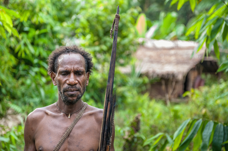 WILD JUNGLE OF NEW GUINEA ISLAND, INDONESIA - JUNE 24: Portrait of papuan man with bow and arrows from Korowai (Kolufo) tribe . June 24, 2012 near Onni Village, New Guinea, Indonesiaのeditorial素材