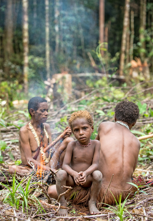 WILD JUNGLE, IRIAN JAYA, NEW GUINEA, INDONESIA - MAY 16, 2016: Papuan woman and little boy of Korowai tribe in the jungle of New Guinea Island. Onni Village. May 16, 2016のeditorial素材