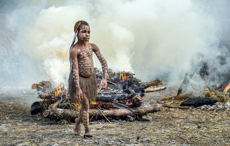 BALIEM VALLEY, WEST PAPUA, INDONESIA, MAY 16th, 2016: Dugum Dani tribe. Unidentified child of Dugum Dani tribe is near the fire in the smoke. 16, May 2016 in West Papua, Indonesia.のeditorial素材