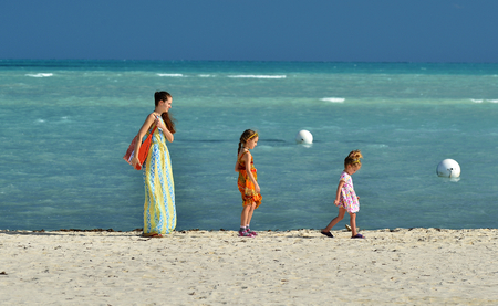 Summer vacation. Mother and cute daughters walking on the sandy beach. blue ocean background. Cuba. Caya Cocoの写真素材