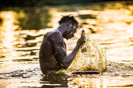 YOUW VILLAGE, ATSY DISTRICT, ASMAT REGION, IRIAN JAYA, NEW GUINEA, INDONESIA - MAY 23, 2016:  Asmat man is bathing in the river and wash away a body paint after the traditional ceremony of his tribeのeditorial素材