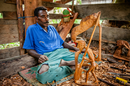 JOW VILLAGE, ASMAT PROVINCE, NEW GUINEA, INDONESIA - JUNE 28: Man from the Asmat Tribe carving with a chisel a statue. Asmat man was making a wood carving. June 28, 2012 Jow Village, Asmat, Indonesiaのeditorial素材