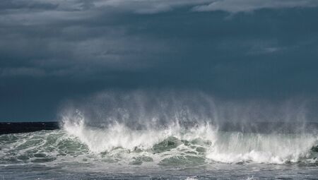 Seascape. Powerful ocean wave on the surface of the ocean. Wave breaks on a shallow bank. Stormy weather, stormy clouds sky background.の写真素材