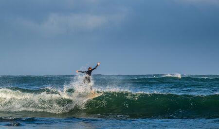 Mossel Bay, South Africa. Surfing the waves. Surfer riding wave with rainbow on storm sky...