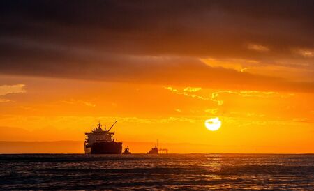 Oil tankers ship at sea on a background of sunset sky. Oil tankers in the ocean. Early in the morning, the sunrise sky. South Africa. Mossel Bayの写真素材