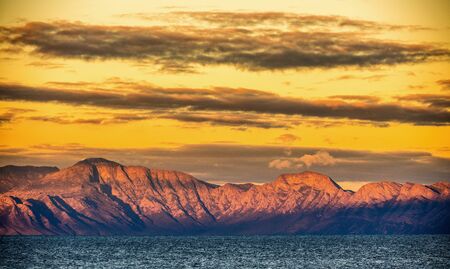 Landscape with mountains, clouds and ocean. Panorama of mountains, wilderness on sunset or sunrise....