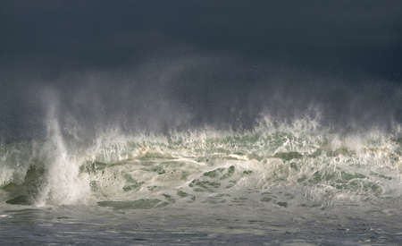 Seascape. Powerful ocean wave on the surface of the ocean. Wave breaks on a shallow bank. Stormy weather, stormy clouds sky background.の写真素材