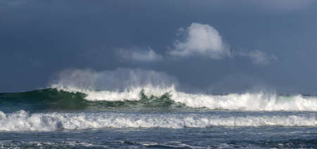 Seascape. Powerful ocean wave on the surface of the ocean. Wave breaks on a shallow bank. Stormy weather, stormy clouds sky background.の写真素材