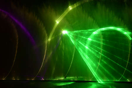 colorful water fountains. Beautiful laser and fountains show. Large multi colored decorative dancing water jet led light fountain show at night. dark background.の写真素材