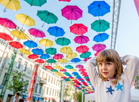 Portrait little girl in the Street decorated with colored umbrellas . Summer day in Saint Petersburg. Russiaの写真素材