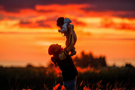 .Portrait of happy mother with baby on sunset background, Summer sunset twilightの写真素材