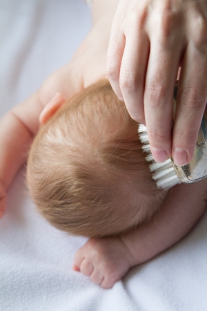 Infant's hair is being gently brushed by mother's loving hand.の写真素材