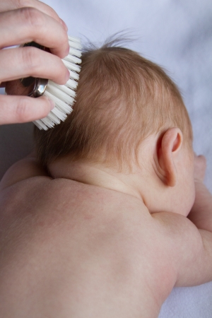 Infant's hair is being gently brushed by mother's loving hand.の写真素材