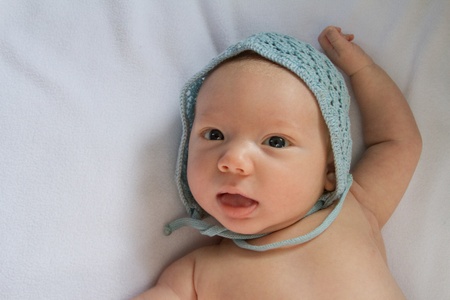 Close up of happy baby wearing hand-crocheted blue cap.