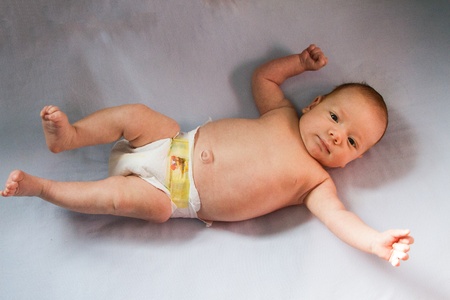 Diapered baby is stretched out full length and smiling.の写真素材