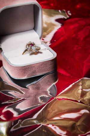 Ring rests in open jewelry box on red velvet backgound.