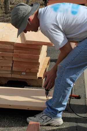 Man drills into wood at construction siteのeditorial素材