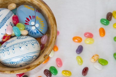 A trio of Easter eggs sit in a bowl with jelly beans scattered around in a horizontal composition...