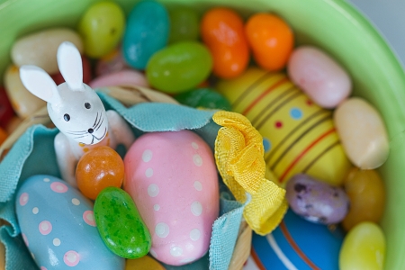 White Easter bunny sits among eggs adn multicolored jelly beans.