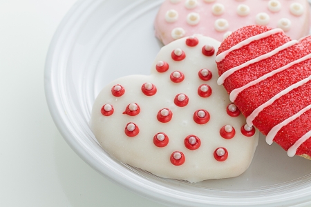 Delicious homemade beautifully decorated valentine cookies rest on plate with horizontal composition and copy space.の写真素材