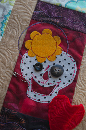 Detail of hand quilted and handmade embroidered wall hanging of Day of the Dead wall hanging.