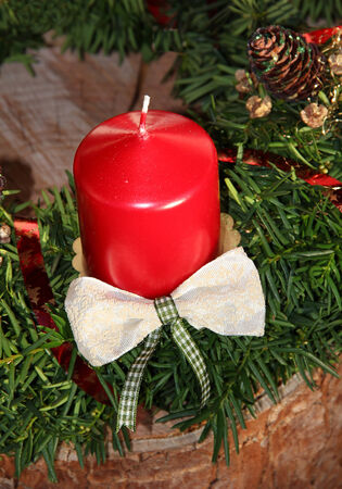 christmas decoration with red candle and jew branches on tree trunkの写真素材