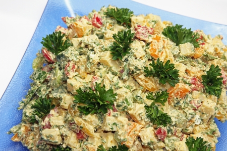 Cheese salad of cubed emmenthal cheese with parsley and dressing on a glass plateの写真素材