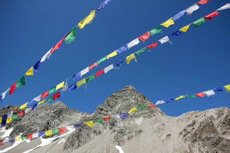 Colorful prayer flags and glacier mountain peak against blue skyの写真素材