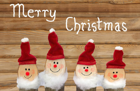 four santa gnomes against wooden planks, hand written text merry christmasの写真素材