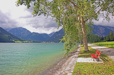 walkway at the lakeside of achensee, with red benchの写真素材