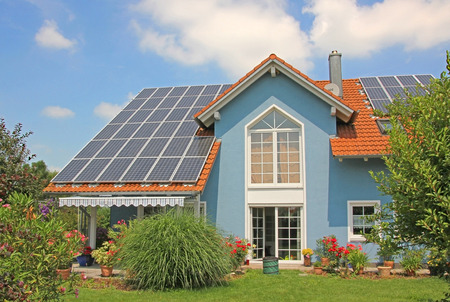 modern new built house and garden, rooftop with solar cells, blue front with lattice window の写真素材