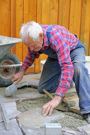 aged senior, paving a patio, professional precision work の写真素材