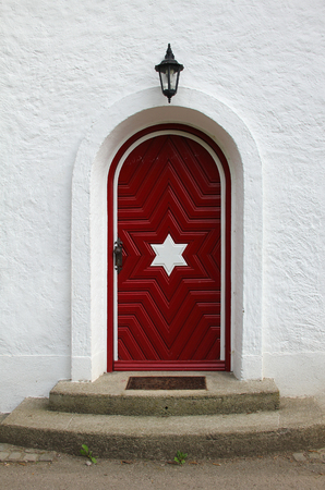 arched vintage entrance with wooden red door, lantern above and two steps の写真素材