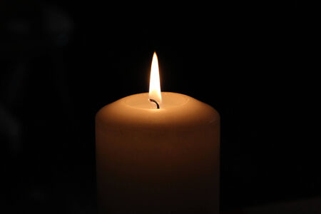 one burning candle against black backgroundの写真素材