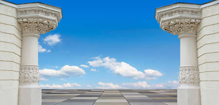 two pillars with beautiful ornate, architectural background. Blue sky with clouds.
