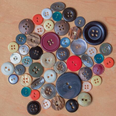 assortment of different buttons in several colors on wooden background