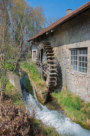 historic water wheel at work in a little creekの写真素材