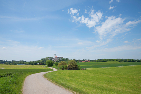 winding way to andechs cloister in idyllic rural bavarian landscape, blue sky with cloudsの写真素材