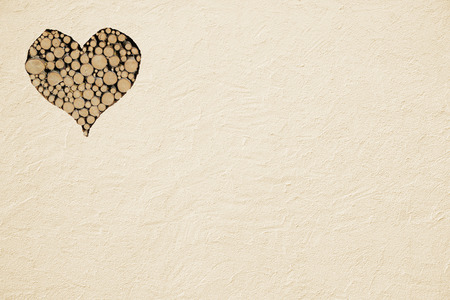 rough beige painted wall with wooden heart, background for love designの写真素材