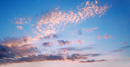 bright blue sky with pink illuminated fleecy clouds at sunrise in the morning