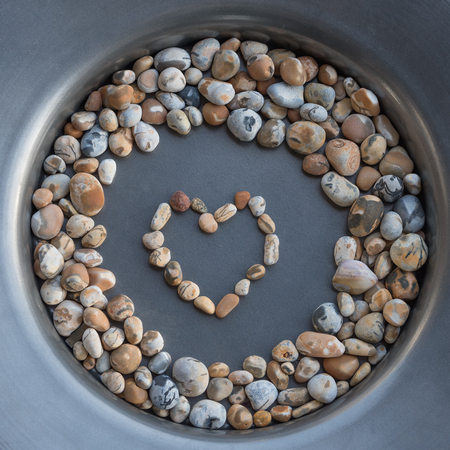 colorful gravel stones in a corcle with heart in the middle on a tin plateの写真素材