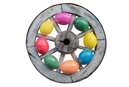 easter decoration - old wooden wheel with colorful tinted easter eggs, isolated on white backgroundの写真素材