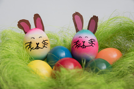 closeup of an easter nest with colorful eggs and funny bunnies