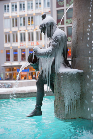 MUNICH, BAVARIA, GERMANY, February 28th, 2018 - one statue at fountain Fischbrunnen, Marienplatz with iceのeditorial素材