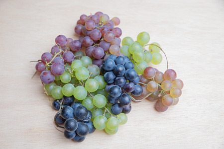 grapes in three colors on wooden board backgroundの写真素材