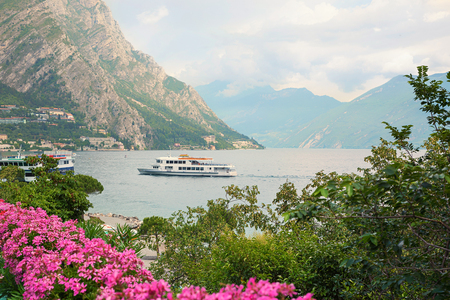 passenger liner en route to limone village, garda lake italy. with pink geranium flowersの写真素材