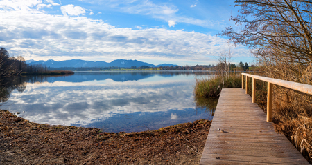 bathing beach lake riegsee with wooden boardwalk and mountain view, landscape upper bavariaの写真素材