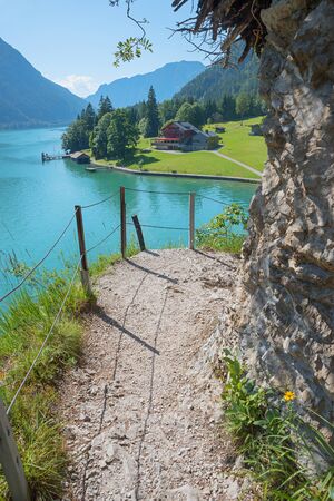 adventurous path with stairs along the lakeside of achensee, view to gaisalm hut. tirolean tourist destination austriaの写真素材