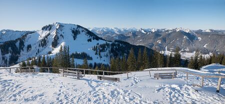 Lookout point with resting benches at wallberg mountain, view to Setzberg summit and bavarian alps. tourist destination near tegernsee, winter landscapeの写真素材